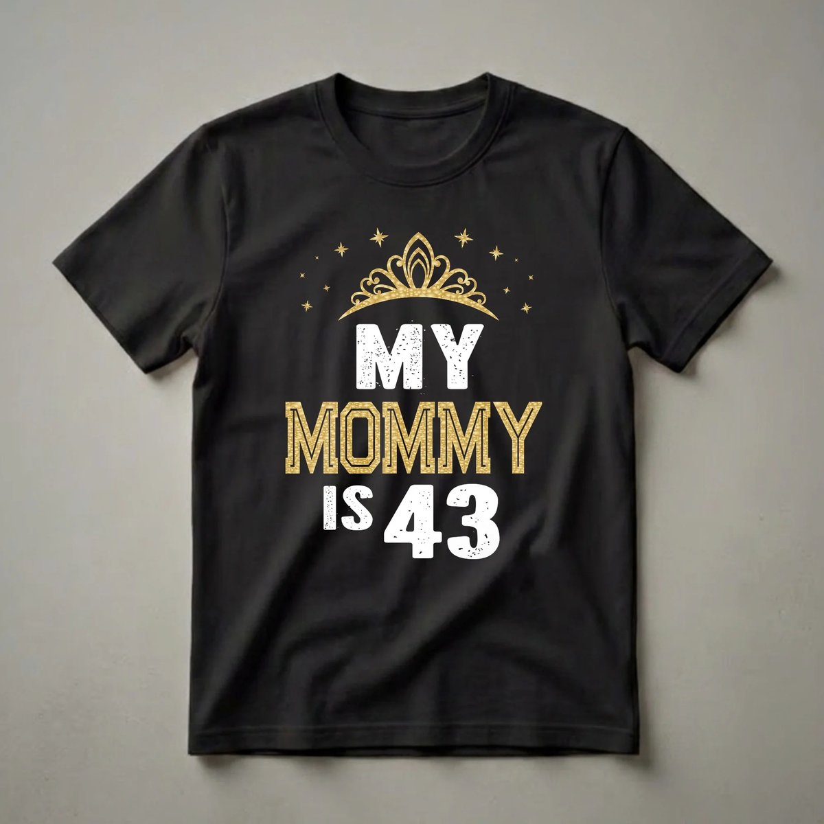 Black t-shirt with white and gold text that reads 'MY MOMMY IS 43', topped with a golden crown and surrounded by golden stars.