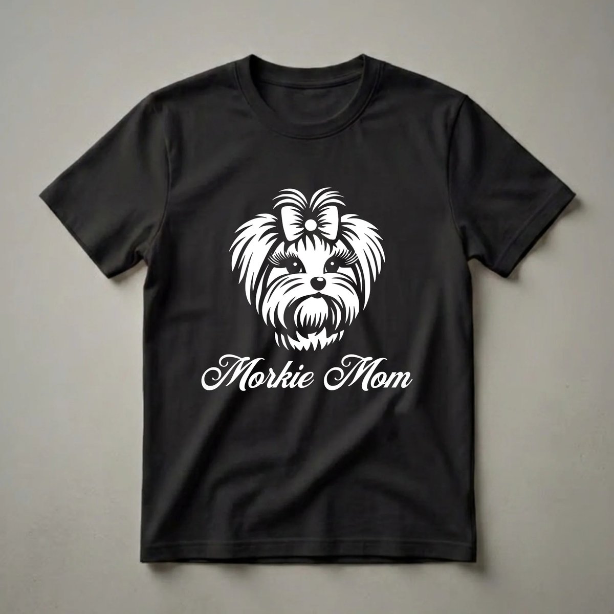 White graphic of a Morkie dog's face with a bow and the text 'Morkie Mom' on a black t-shirt.