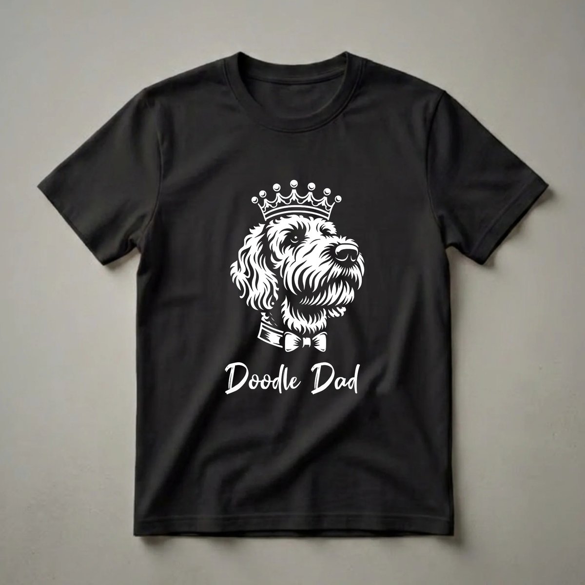 White graphic on a black shirt showing a Labradoodle dog wearing a crown and a bowtie, with the text 'Doodle Dad' below.