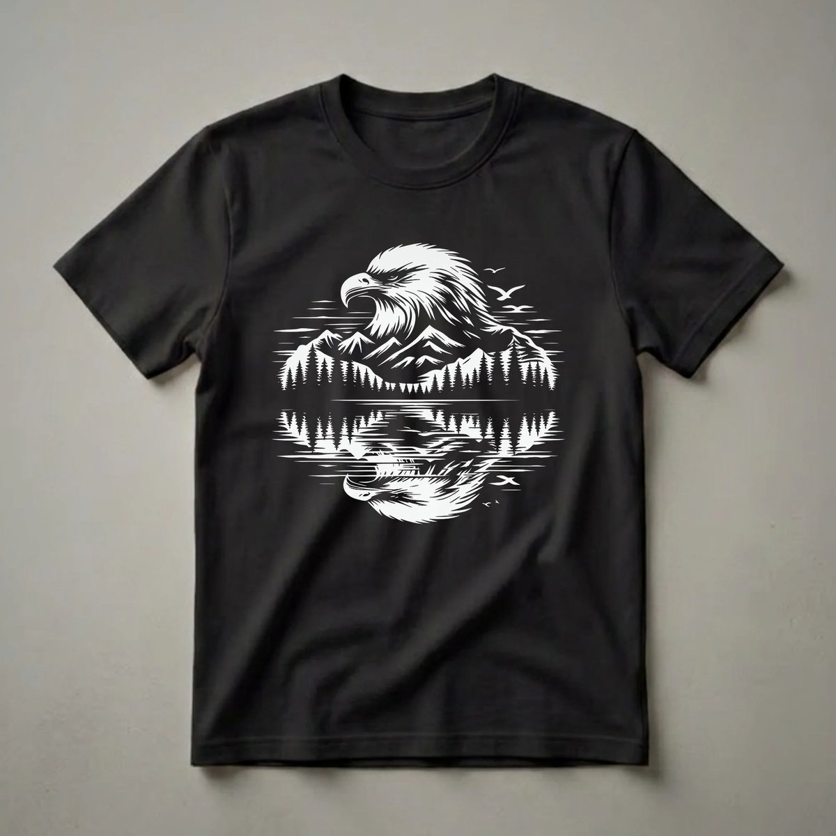 Black t-shirt with a white graphic design of a bald eagle's head above a mirrored landscape of mountains, pine trees, and birds in flight reflected in water.