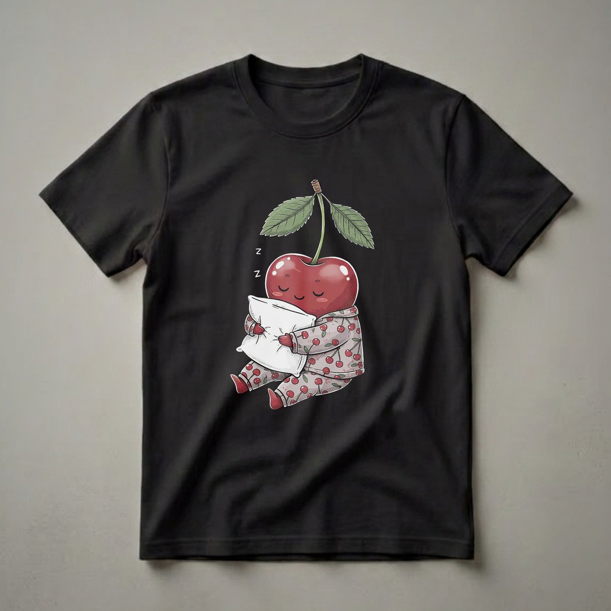Black t-shirt featuring a cartoon cherry wearing pajamas and hugging a pillow, with 'Z's indicating sleep.