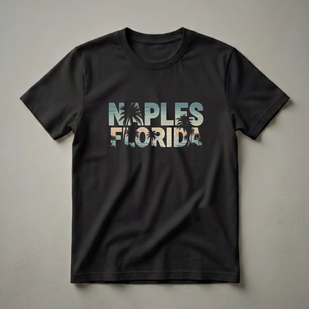 Black t-shirt with 'NAPLES FLORIDA' text filled with a retro sunset scene featuring palm trees, ocean waves, and a soft sky.