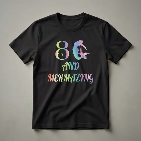 Black t-shirt with a watercolor rainbow gradient graphic that reads '8 AND MERMAZING' and features a mermaid silhouette.