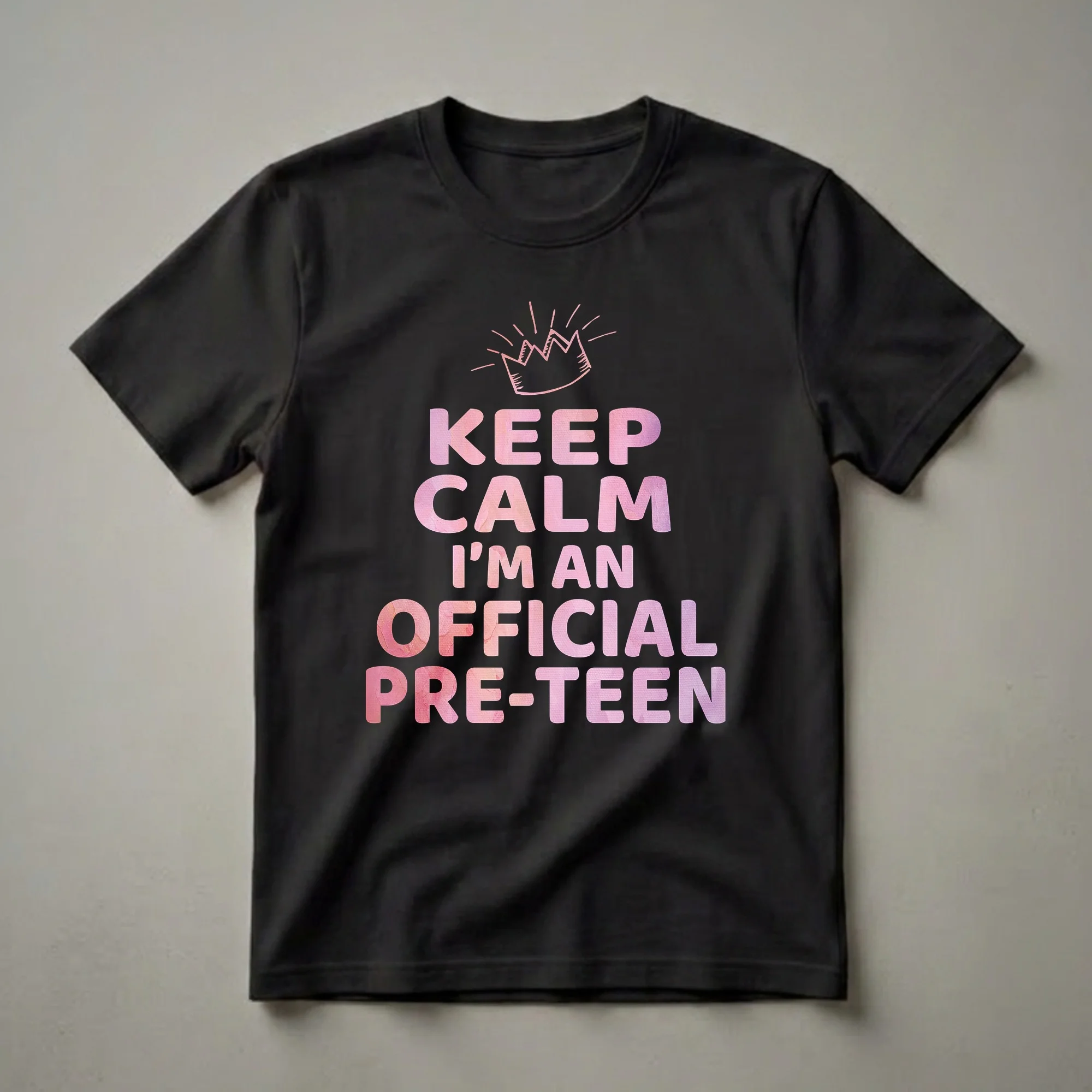 Black t-shirt with pink watercolor text that says 'KEEP CALM I'M AN OFFICIAL PRE-TEEN' and a pink watercolor crown graphic above the text.