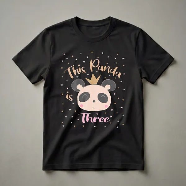 Black t-shirt with a graphic of a cute panda face wearing a gold crown, surrounded by pink, gold, and silver stars, with the text 'This Panda is Three' in decorative fonts.