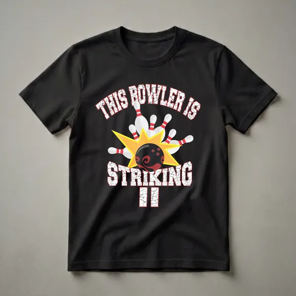Black t-shirt with white and red cracked text reading 'THIS BOWLER IS STRIKING II' and a graphic of a bowling ball hitting pins.