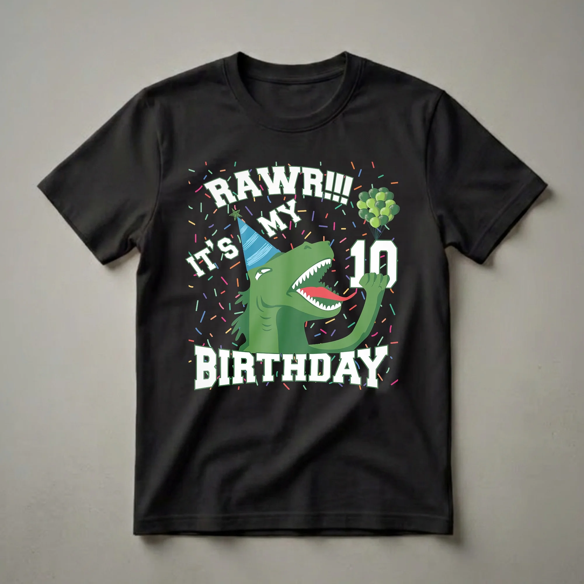 Black t-shirt with a green cartoon T-Rex wearing a blue party hat, surrounded by colorful confetti and green balloons, with the text "RAW R!!! MY IT'S 10 BIRTHDAY" in white block letters.