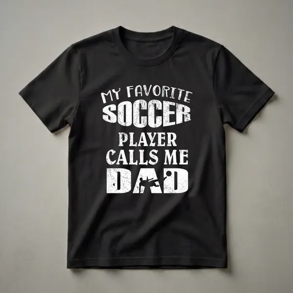 Black t-shirt with white distressed text that reads 'My Favorite Soccer Player Calls Me Dad' and a silhouette of a soccer player kicking a ball.