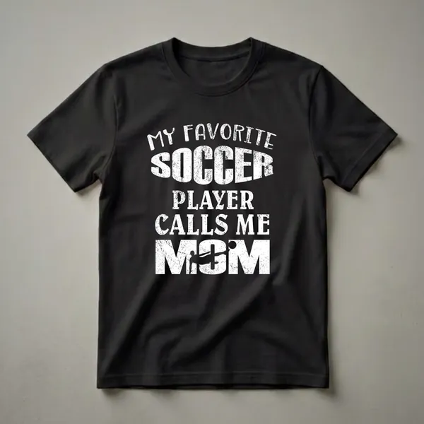 Black t-shirt with white distressed text that reads 'My Favorite Soccer Player Calls Me Mom', featuring a silhouette of a soccer player kicking a ball.