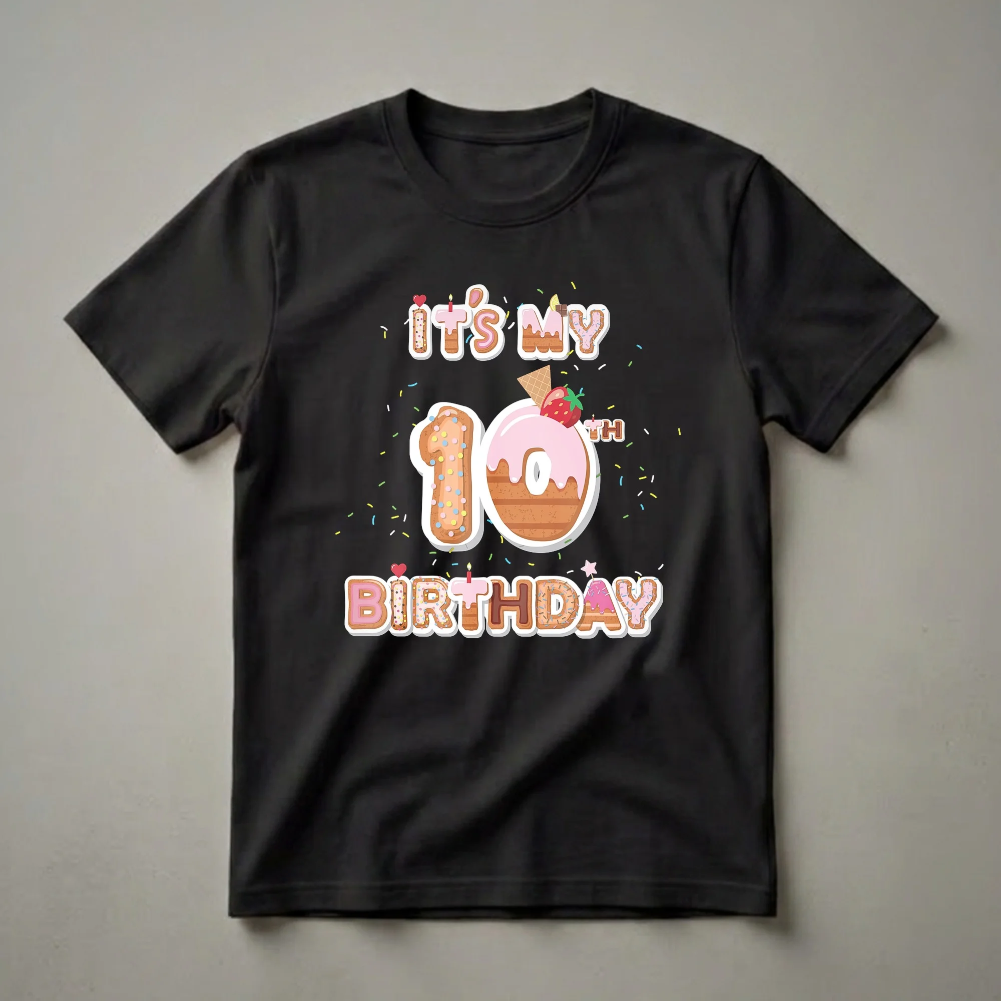 Black t-shirt with a graphic design that reads 'It's My 10th Birthday' with numbers and letters styled as donuts and cookies, adorned with sprinkles, a strawberry, and a waffle cone.