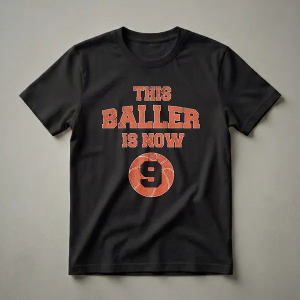 Black t-shirt with distressed orange text reading 'THIS BALLER IS NOW 9' above a distressed basketball graphic featuring the number 9.