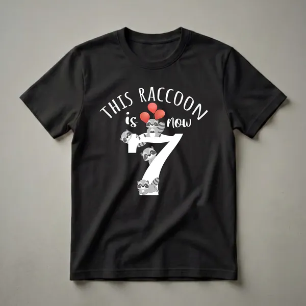 Black t-shirt with a white graphic that reads 'THIS RACCOON is now 7' featuring cartoon raccoons and red balloons.