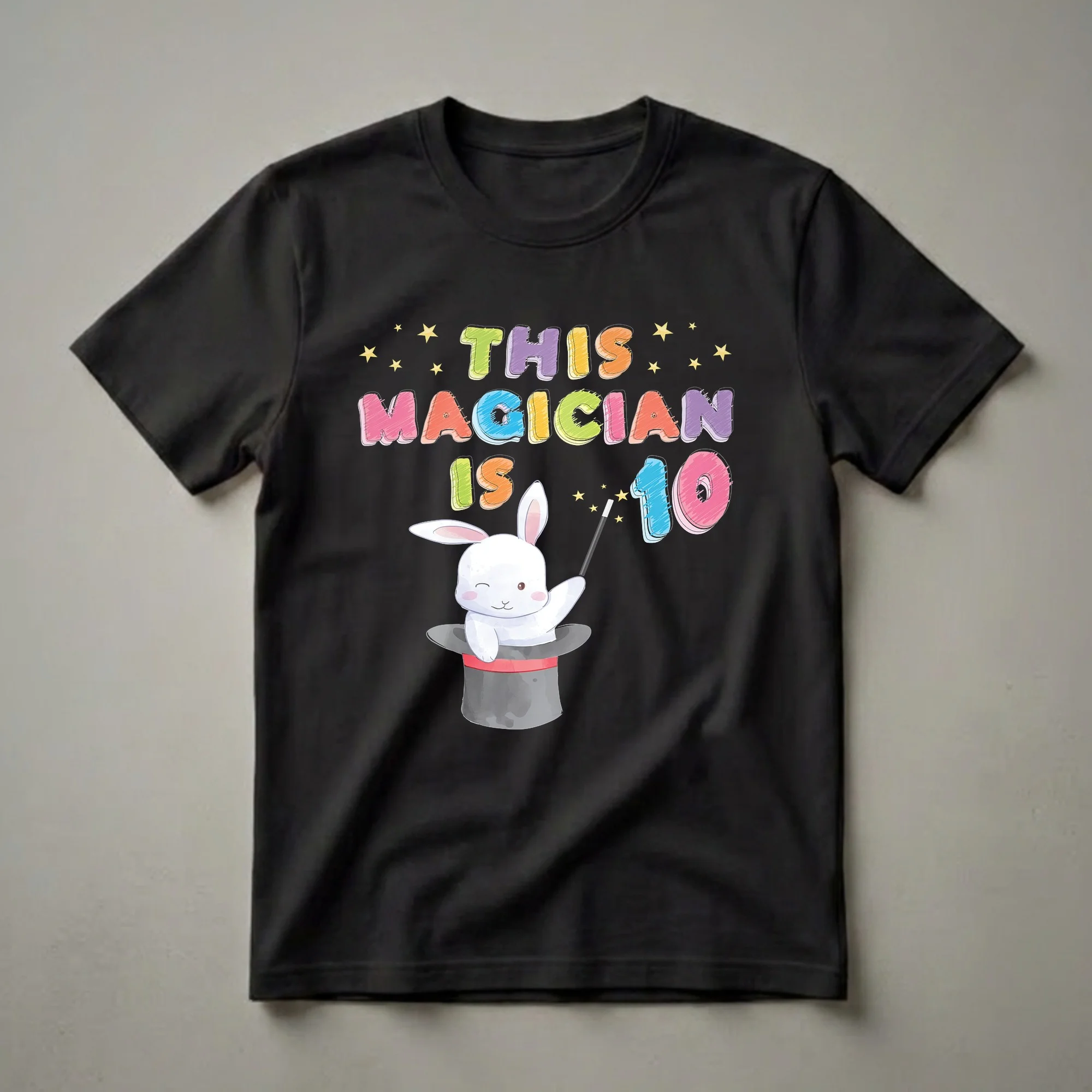 Black t-shirt featuring colorful text that reads 'THIS MAGICIAN IS 10' and a watercolor illustration of a white rabbit in a magician's hat holding a wand with stars.
