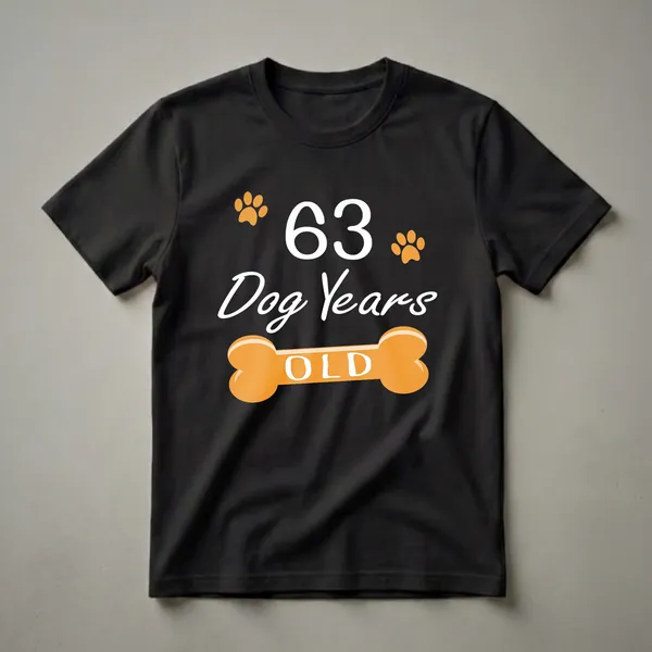 Black t-shirt with white text reading '63 Dog Years OLD' and orange paw prints and a dog bone graphic.