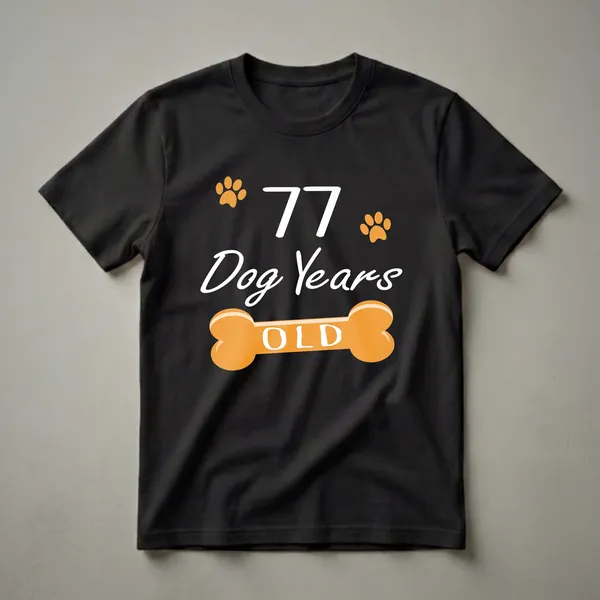 Black t-shirt with white text reading '77 Dog Years Old' and orange paw prints and a dog bone graphic.