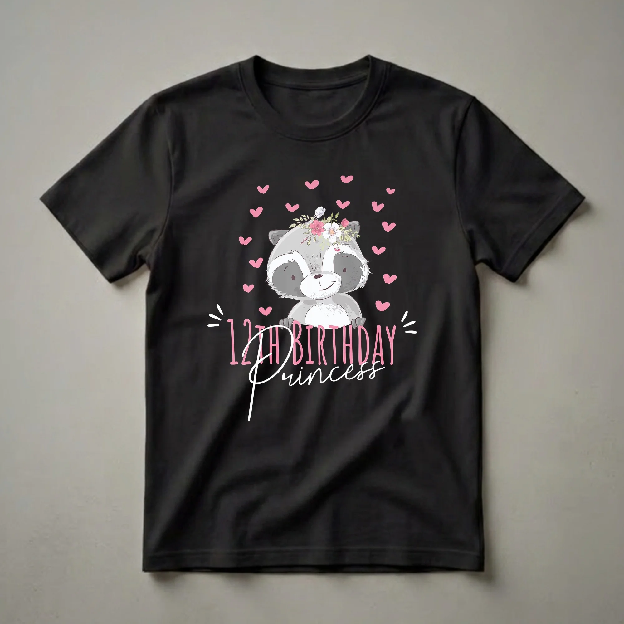Black t-shirt featuring a cartoon raccoon wearing a floral crown, surrounded by pink hearts, with the text '12th Birthday Princess' in pink and white.