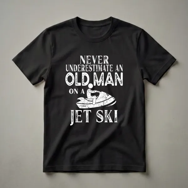 Black t-shirt with white distressed text that reads 'NEVER UNDERESTIMATE AN OLD MAN ON A JET SKI' above a graphic of a person riding a jet ski.