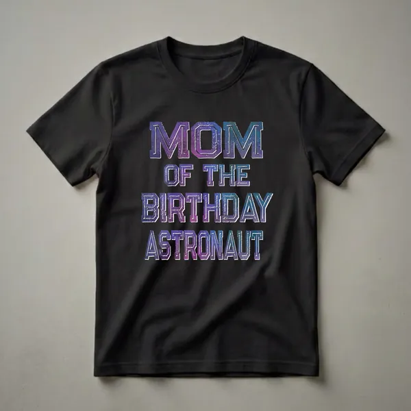 A white t-shirt with distressed galaxy print text that reads 'MOM OF THE BIRTHDAY ASTRONAUT' in large letters.