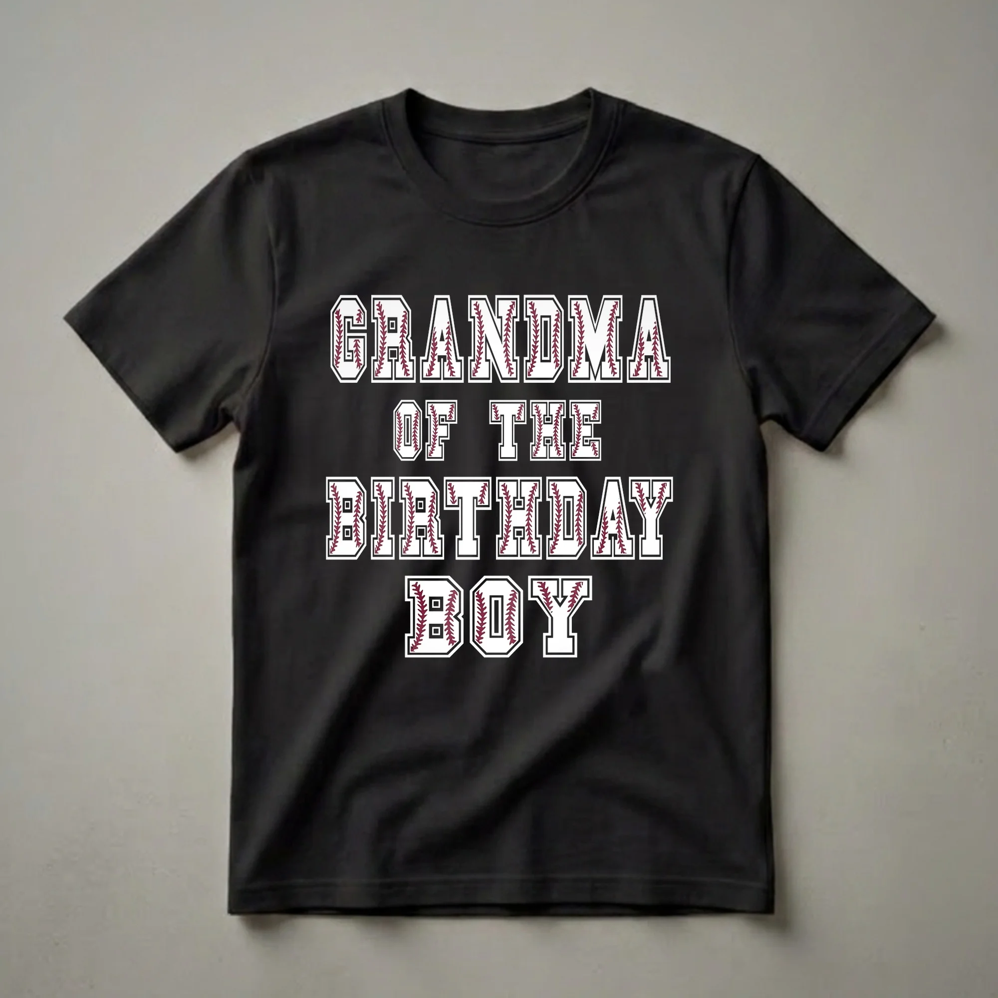 White t-shirt with black and maroon text that reads 'GRANDMA OF THE BIRTHDAY BOY' in a collegiate font, with baseball stitching filling the letters.
