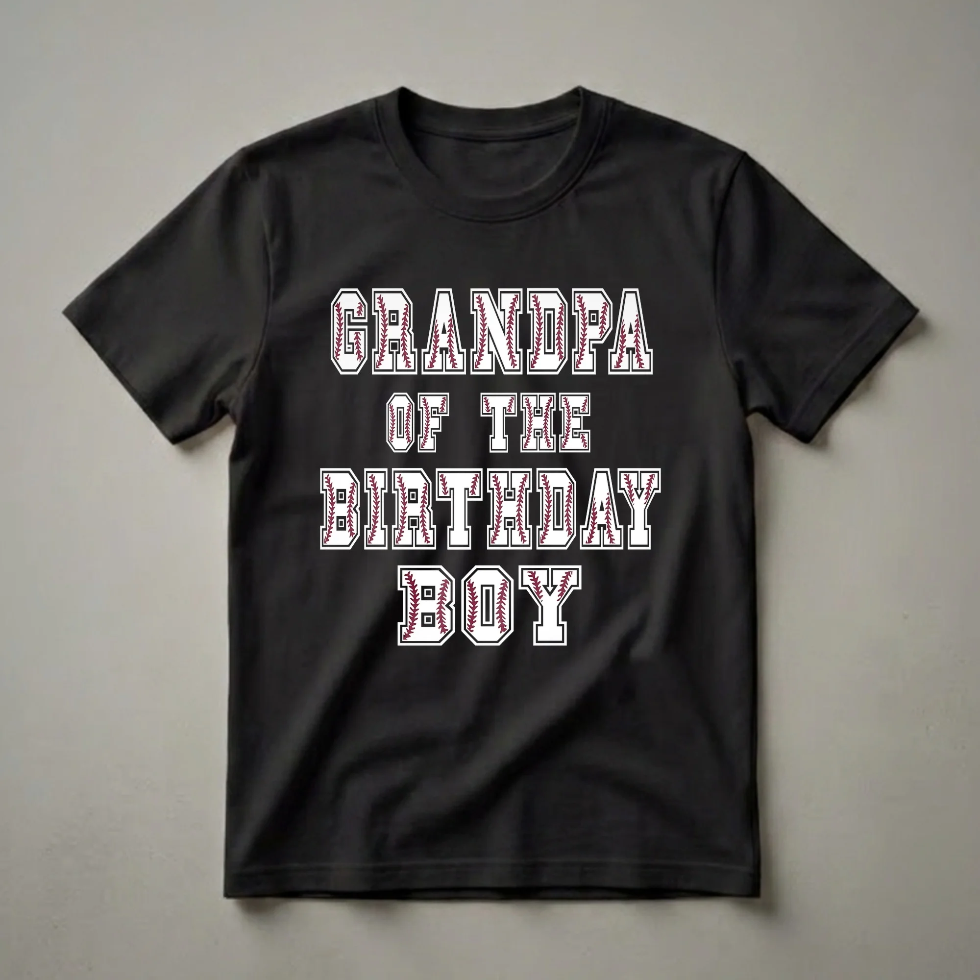White t-shirt with black and maroon collegiate lettering that reads 'GRANDPA OF THE BIRTHDAY BALLER', featuring baseball stitching within the letters.