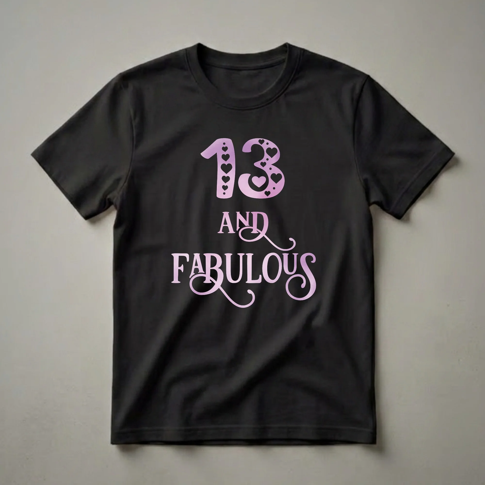 Black t-shirt with pink watercolor gradient graphic that reads '13 AND FABULOUS', with the number 13 decorated with hearts and dots.