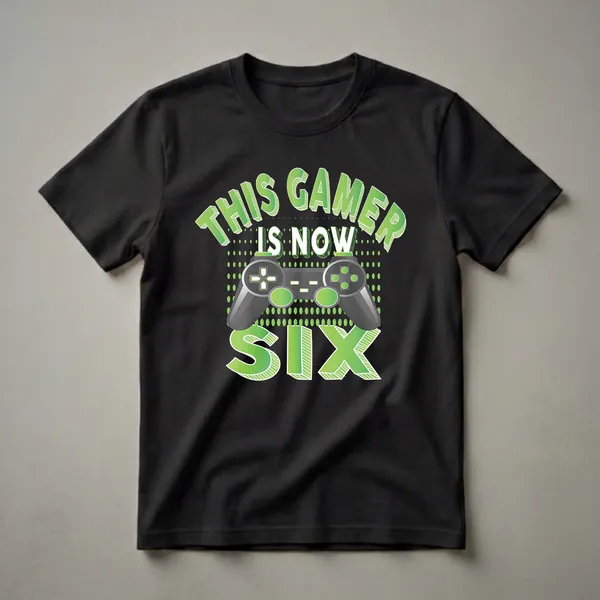 Black t-shirt with green gradient text 'THIS GAMER IS NOW SIX' and a gray video game controller graphic with green accents.