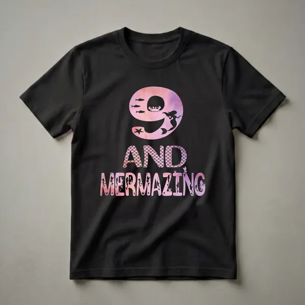 Black t-shirt graphic with a pink and purple watercolor filled number 9, featuring a mermaid silhouette, fish, and crab, followed by the text "AND MERMAZING" with similar watercolor fill and ocean-themed silhouettes.