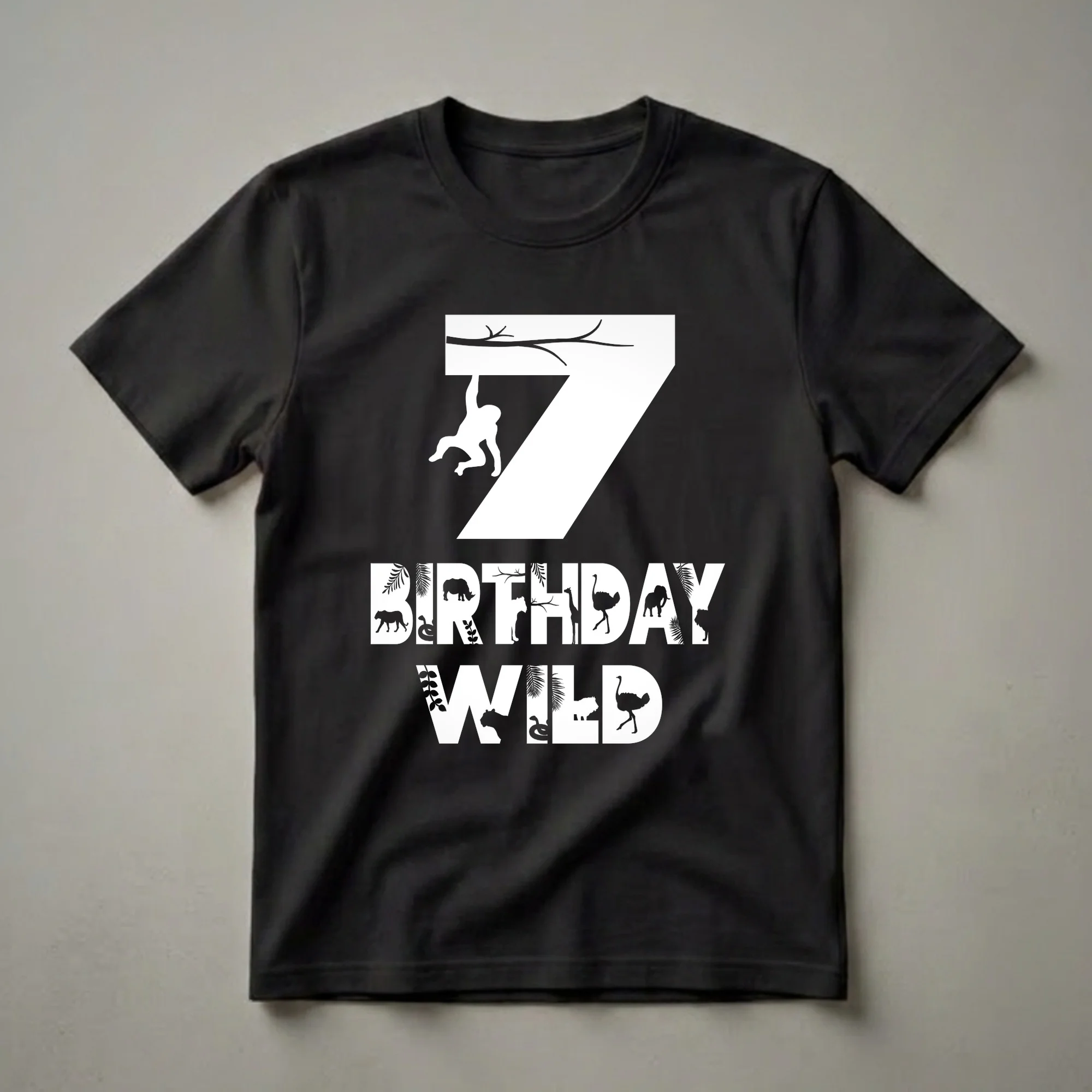 Black t-shirt with white graphic of the number 7 and hanging monkey, plus BIRTHDAY WILD text filled with jungle animals like tiger, snake, rhino, giraffe, elephant, ostrich, and lion.