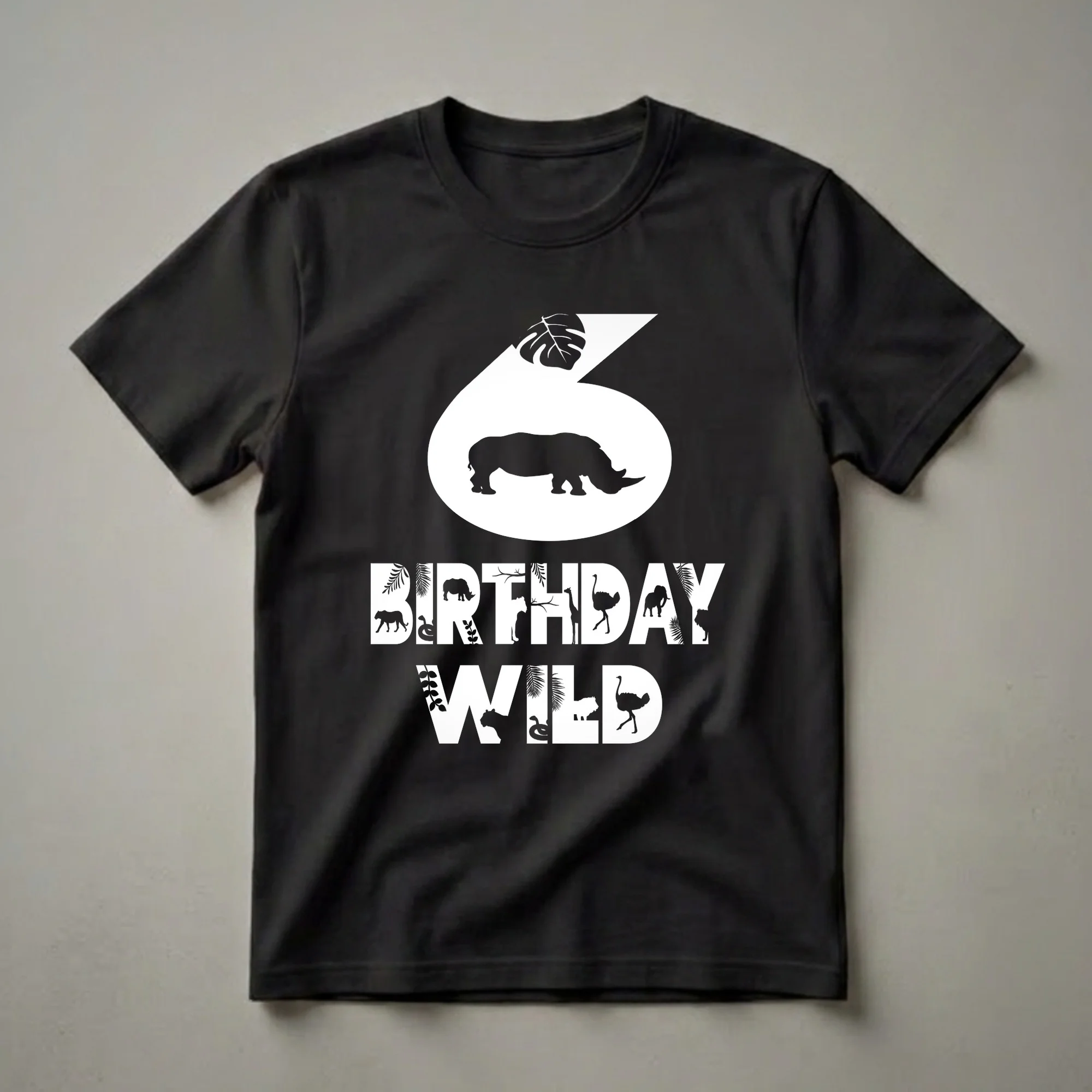Black t-shirt with a white graphic design for a 6th birthday, featuring the number 6 with a rhinoceros silhouette and the words BIRTHDAY WILD filled with various jungle animals and tropical leaves.