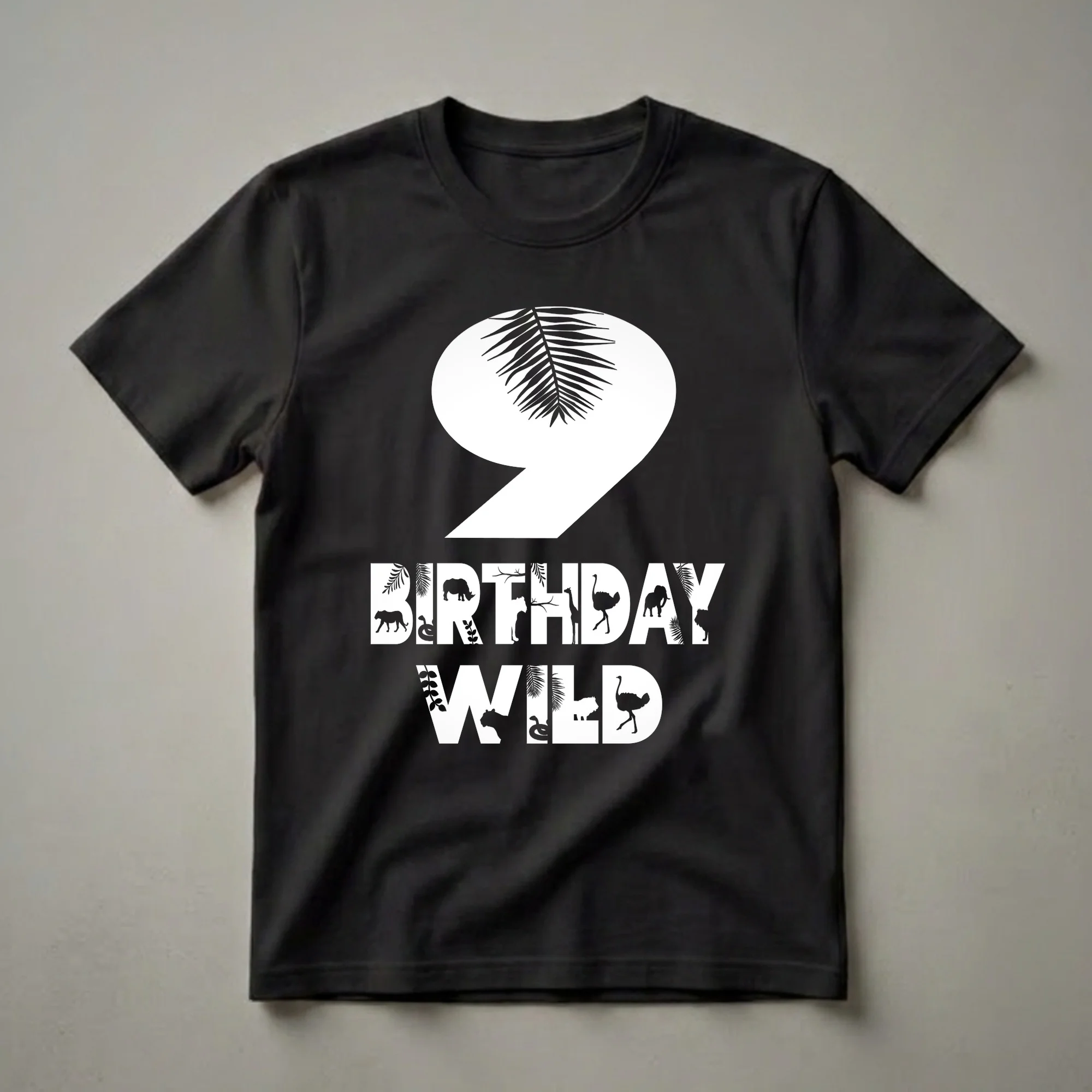 Black graphic t-shirt with a large white number 9 overlayed with a palm frond, and the words BIRTHDAY WILD filled with silhouettes of zoo animals and tropical leaves.