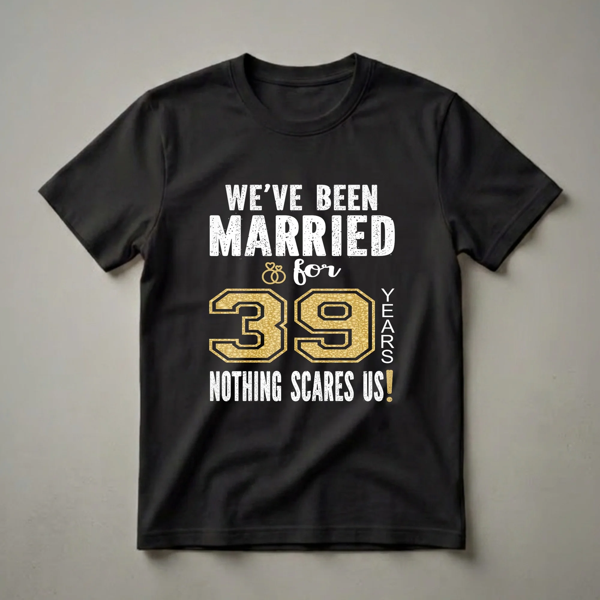 Black t-shirt with white distressed text reading 'WE'VE BEEN MARRIED & for 39 YEARS NOTHING SCARES US!' and a large gold textured number '39' with interlocking rings.