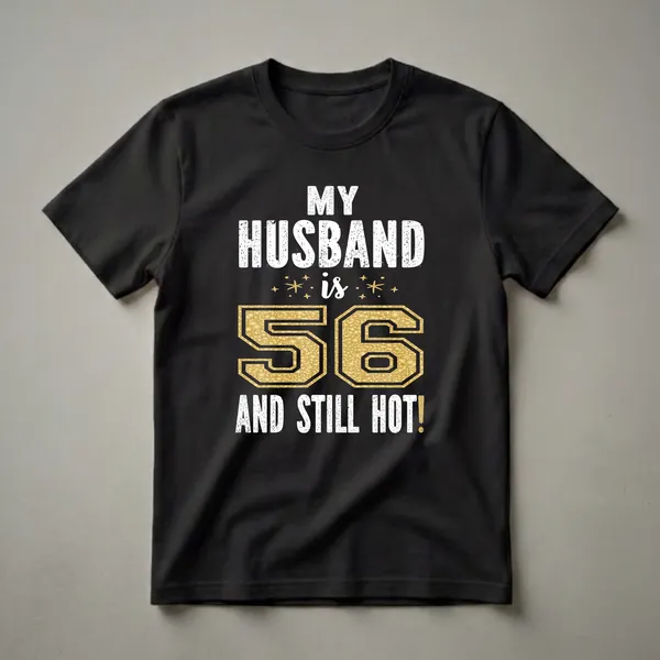 Black t-shirt with white distressed text reading 'MY HUSBAND IS 56 AND STILL HOT!' and a large gold textured number '56'.