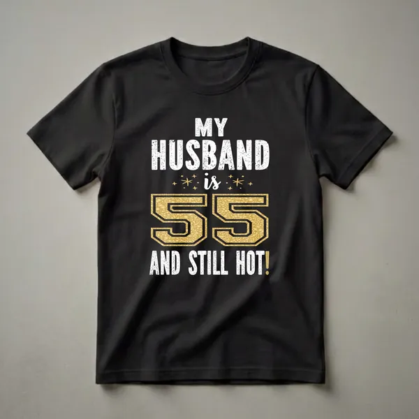 Black t-shirt with white distressed text reading 'MY HUSBAND IS 55 AND STILL HOT!' and a large gold textured number '55' in the center.