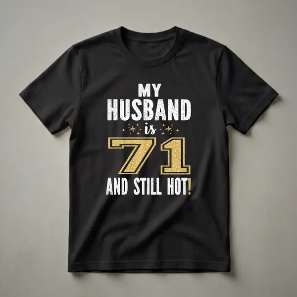 Black t-shirt with white distressed text reading 'MY HUSBAND IS 71 AND STILL HOT!' and a large gold glitter number 71 with star accents.