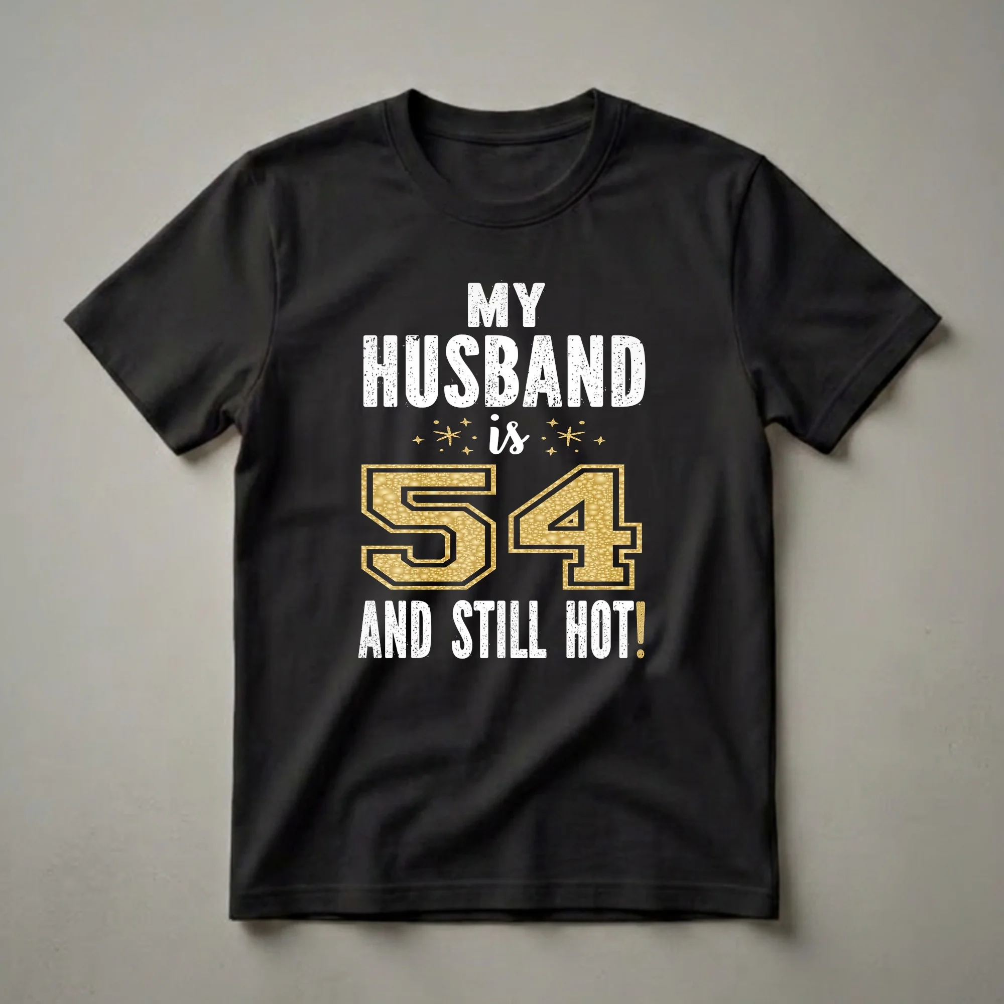 Black t-shirt with white distressed text 'MY HUSBAND IS 54 AND STILL HOT!' and a large gold glitter textured number 54.