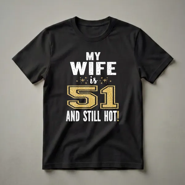 Black t-shirt with distressed white text reading "MY WIFE" and "AND STILL HOT!", with a large gold textured number "51" and small gold star accents.