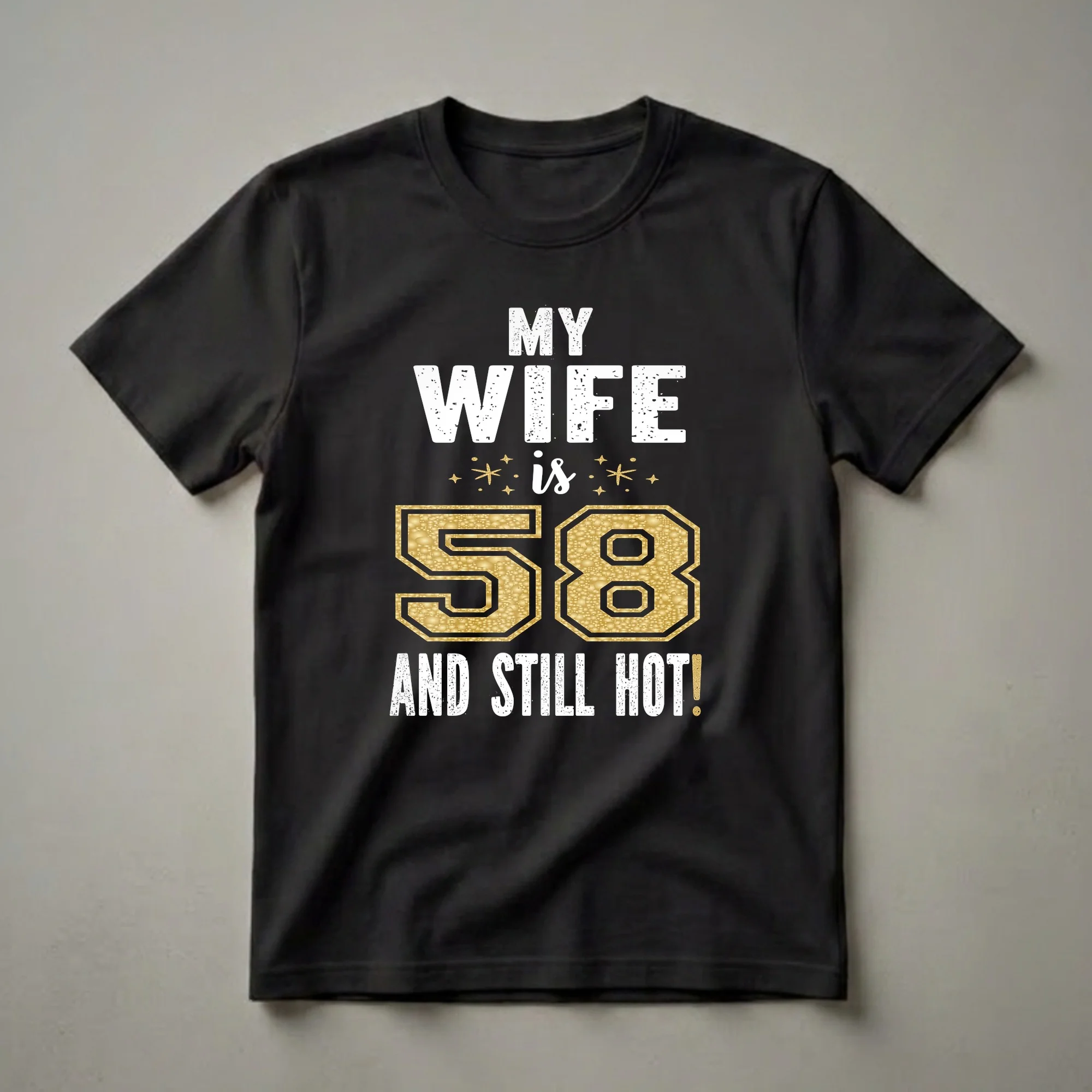 Black t-shirt with white distressed text reading 'MY WIFE is 58 AND STILL HOT!' with a large gold glitter textured number 58.