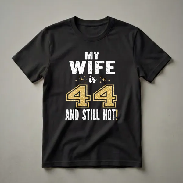 Black t-shirt with white distressed text that reads "MY WIFE is 44 AND STILL HOT!" with a large glitter gold number 44 and gold stars.