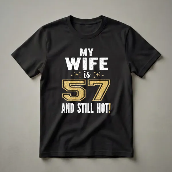 Black t-shirt with white distressed text reading 'MY WIFE is 57 AND STILL HOT!' and a large gold textured number 57 with gold starbursts.
