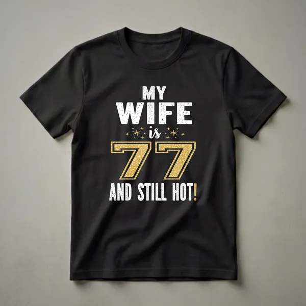 Black t-shirt with white distressed text that reads "MY WIFE is 77 AND STILL HOT!" The number 77 is in gold glitter with a black outline, and small gold stars are scattered around the text.