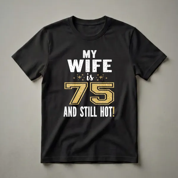 Black t-shirt with white distressed text reading 'MY WIFE is 75 AND STILL HOT!' with a large gold glitter textured number 75 and small gold star accents.