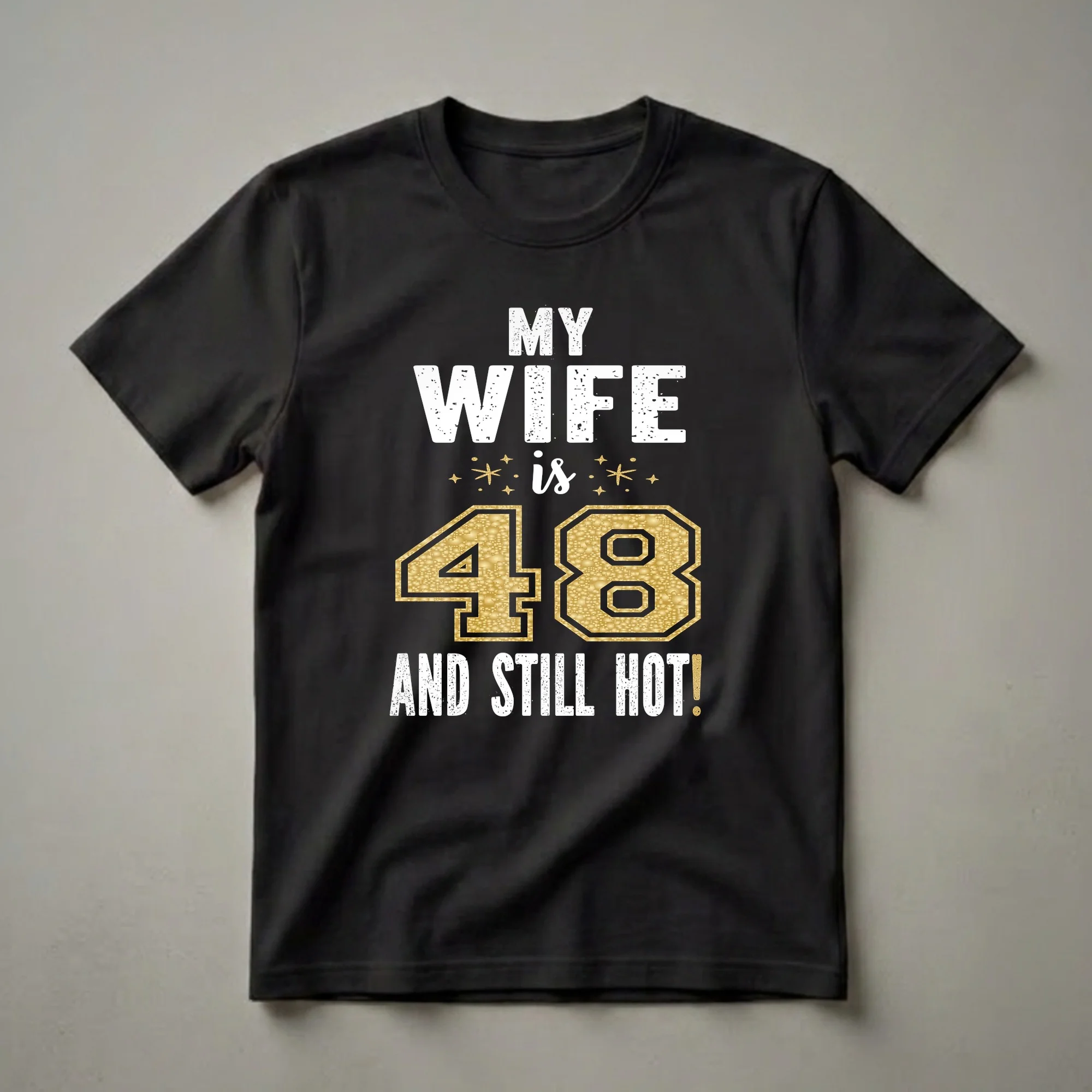 Black t-shirt with distressed white text 'MY WIFE is 48 AND STILL HOT!' and a large gold glitter number '48' with gold star accents.