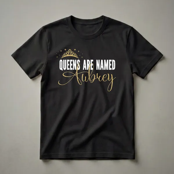 Black t-shirt with distressed white text 'QUEENS ARE NAMED' and a shimmering gold script name 'Aubrey', topped with a golden crown and stars.