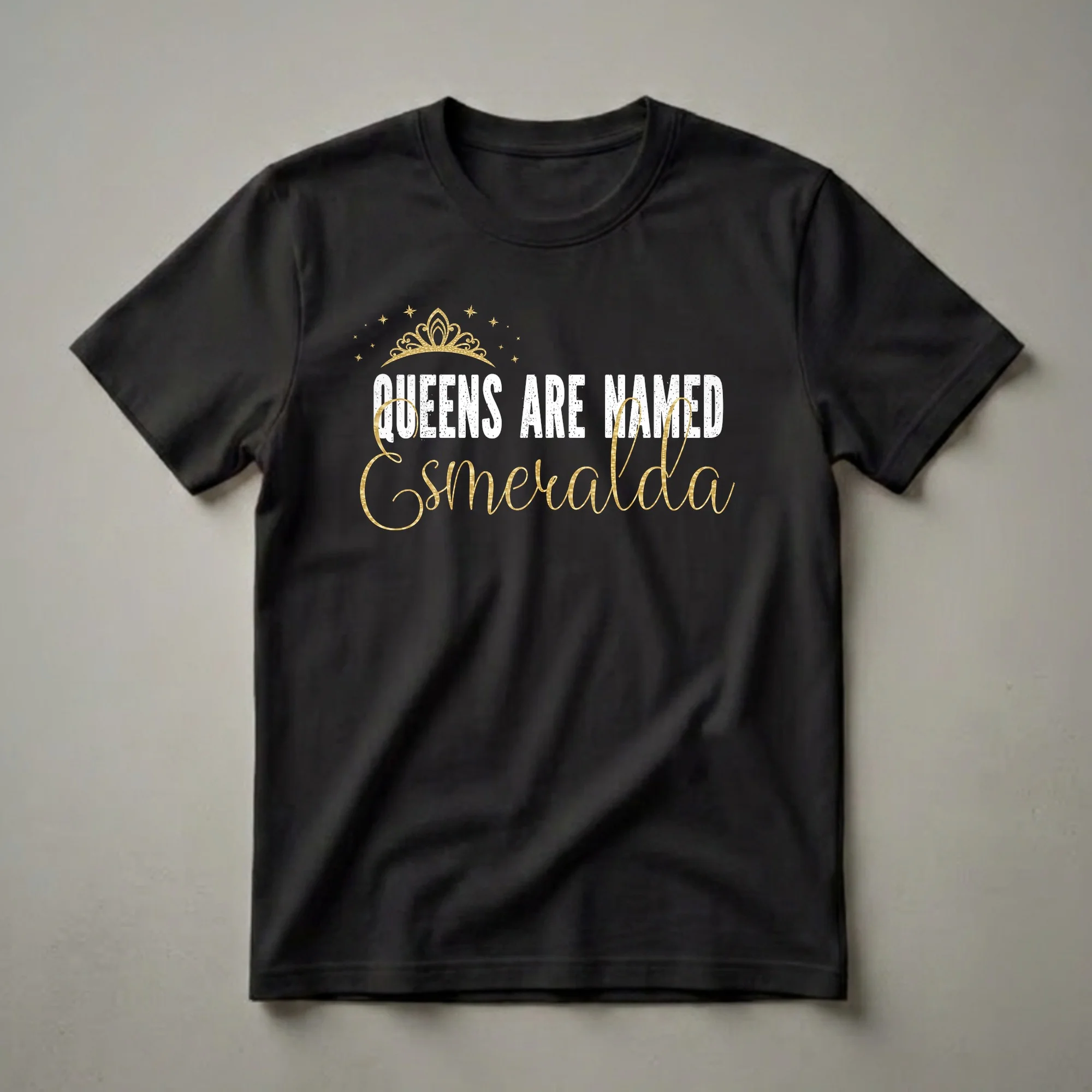 Black t-shirt with a graphic design featuring a golden crown and stars above distressed white text reading 'QUEENS ARE NAMED' and elegant gold script text reading 'Esmeralda'.