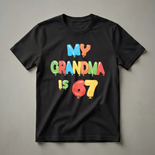 Black t-shirt with colorful balloon letters spelling out "MY GRANDMA IS 67" and small grey strings hanging below.