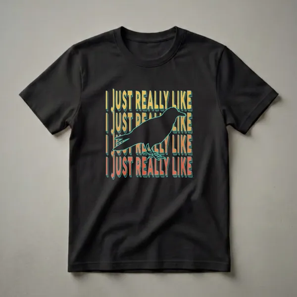 Black graphic t-shirt featuring a silhouette of a raven with the repeating text 'I JUST REALLY LIKE' in retro orange and yellow font with teal outlines.