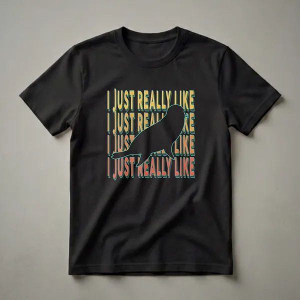 Black graphic t-shirt featuring a black seal silhouette with repeating text 'I JUST REALLY LIKE' in yellow, orange, and red retro fonts.