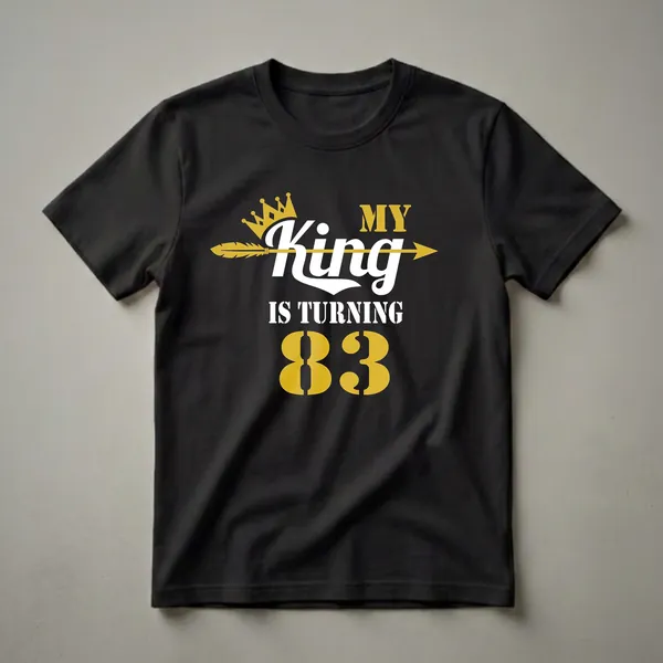 Black t-shirt with gold and white text that reads 'MY KING IS TURNING 83' with a gold crown and arrow graphic.