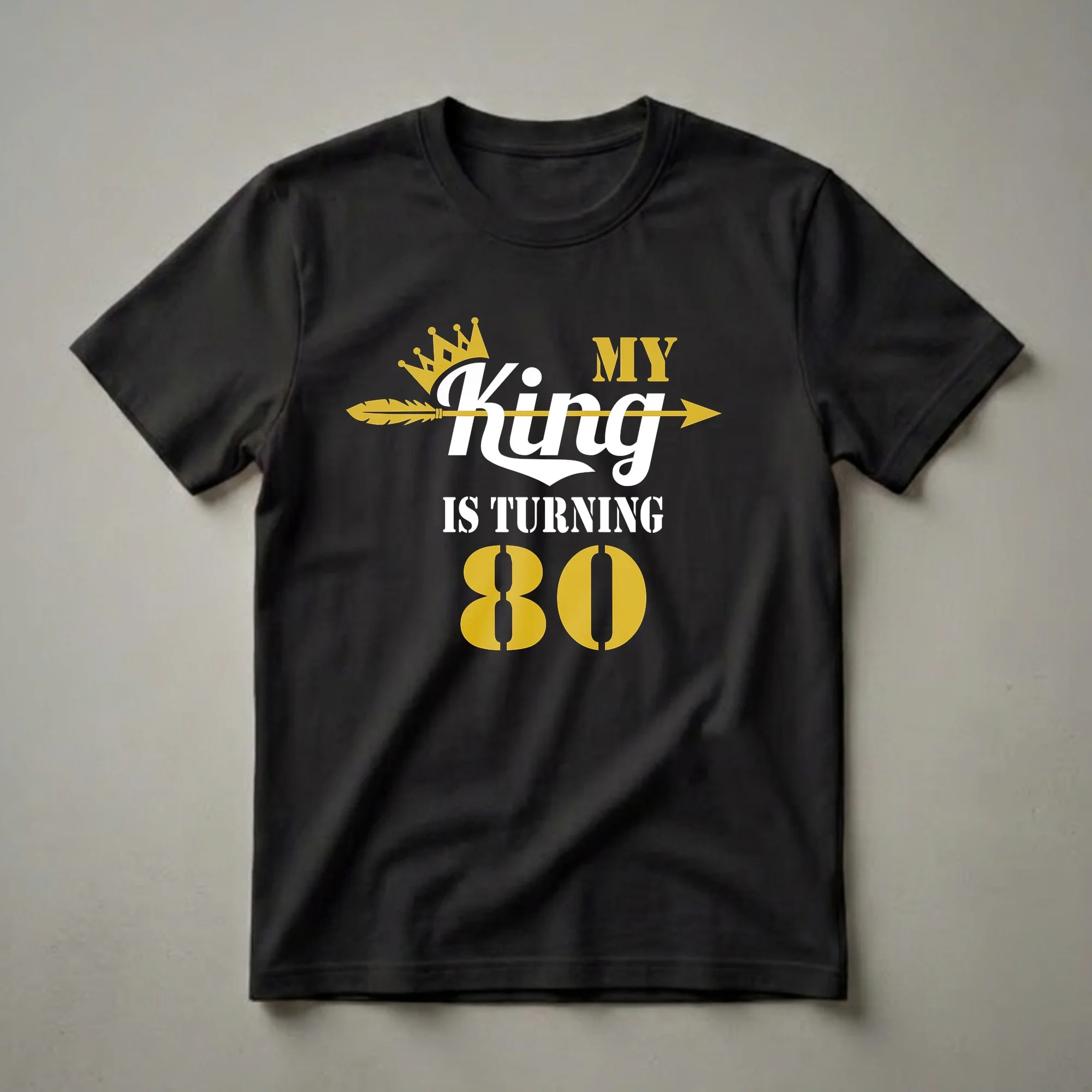 Black t-shirt with white and gold text that reads 'MY King IS TURNING 80', featuring a gold crown and a gold arrow.