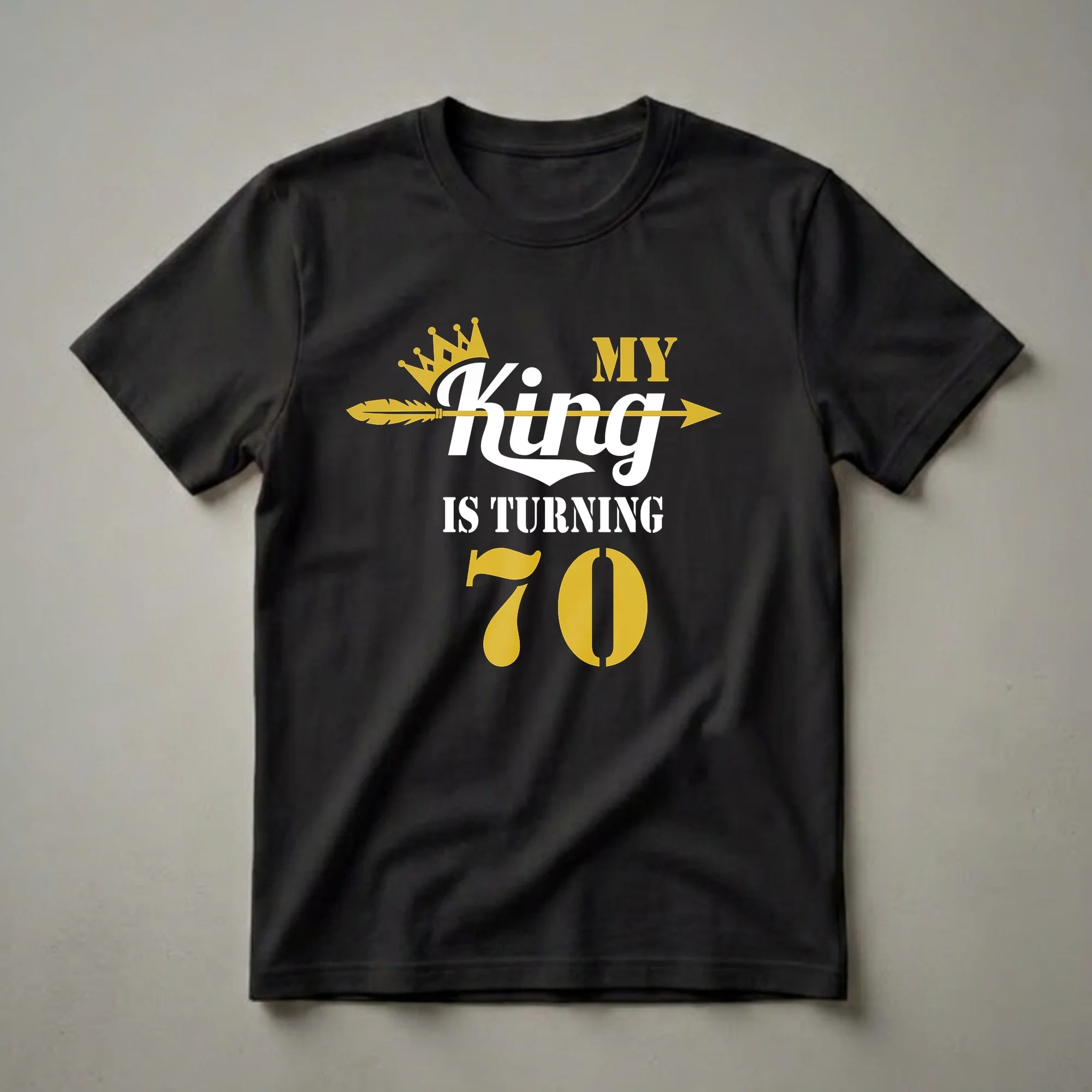 Black t-shirt with gold and white text that reads 'MY King IS TURNING 70', featuring a gold crown and a gold arrow.